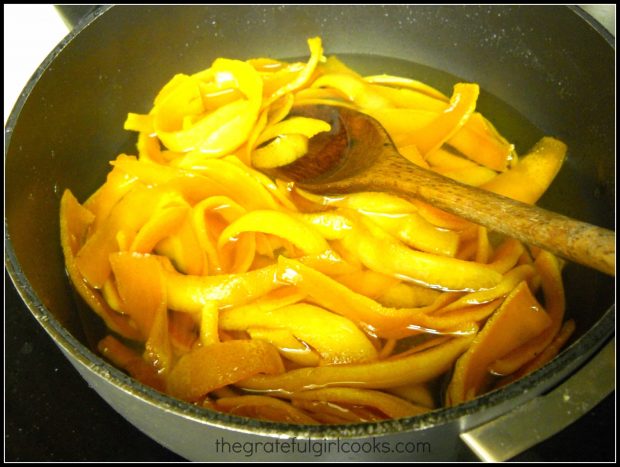 Boiling strips of orange peels in water in saucepan, for candied citrus peels.