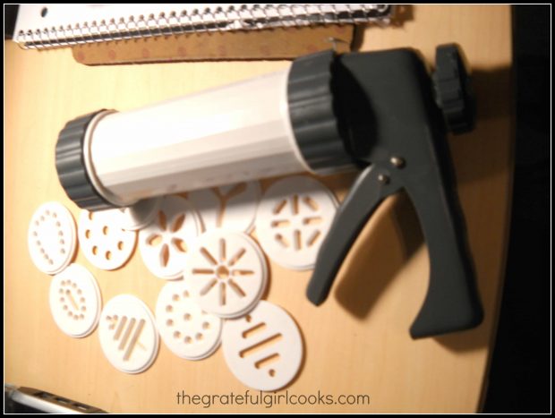 A cookie press is used to make holiday spritz cookies.