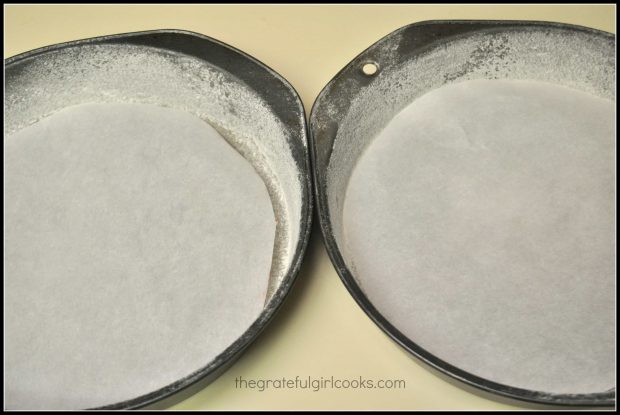 Two cake pans are dusted with flour, and parchment paper is placed on bottom.