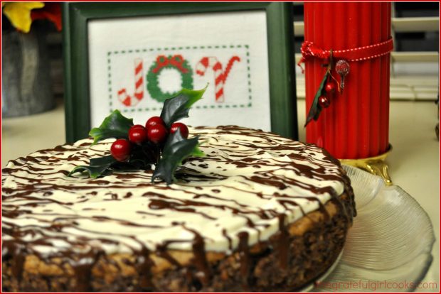 Chocolate fudge truffle cheesecake on platter, with Christmas candle and picture.