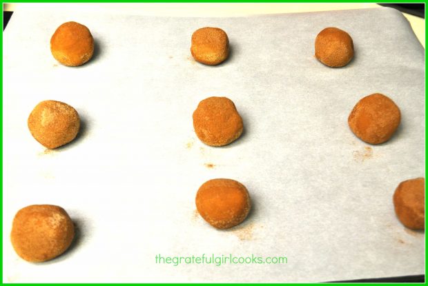 Snickerdoodles dough balls on parchment paper covered cookie sheet, ready to bake.