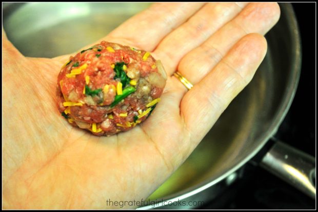 Beef shaped into a meatball being held in a hand