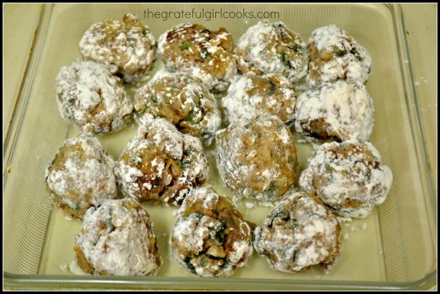 Flour coated meatballs in a glass baking dish.