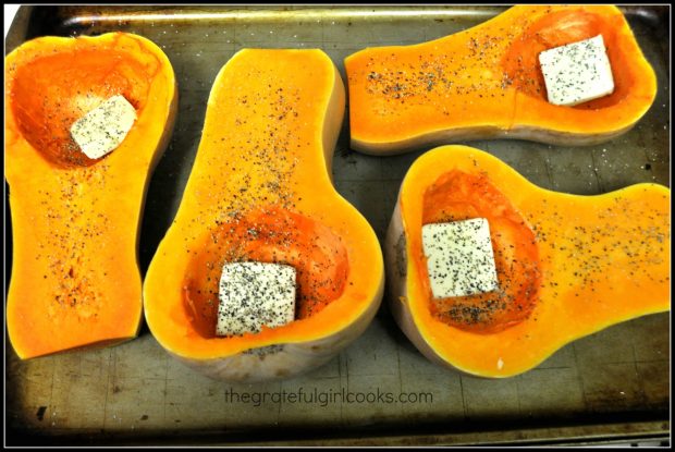 Butternut squash are halved, seeded, and butter, salt and pepper added before baking.