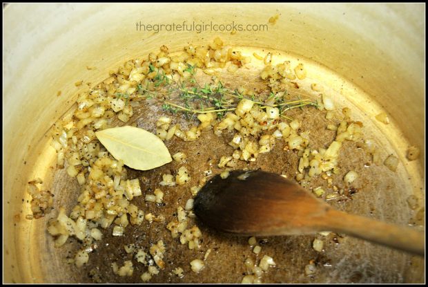 Onion, thyme, and bay leaf are cooked to season butternut squash soup.