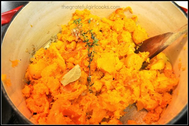 Baked butternut squash is scooped out of skin and added to soup pot.