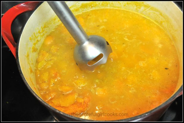 Butternut squash soup is blended with an immersion blender.