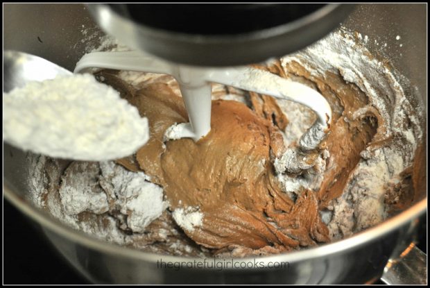 Flour is added to chocolate crinkle cookies batter a little at a time, and mixed.