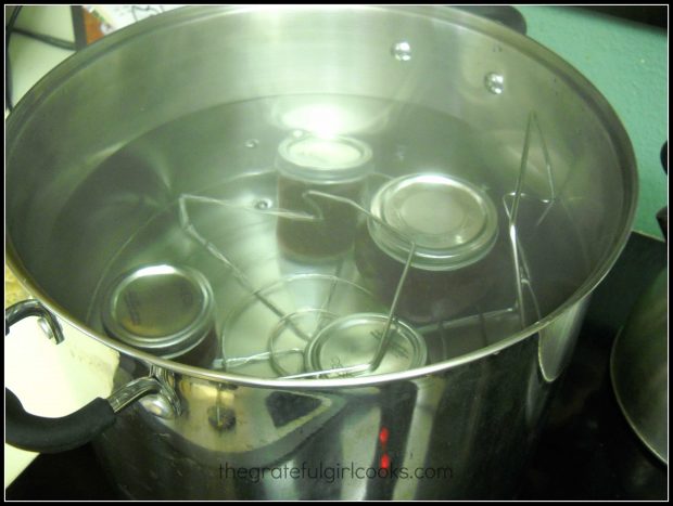 Loading jars of chocolate raspberry sauce into canner for processing.