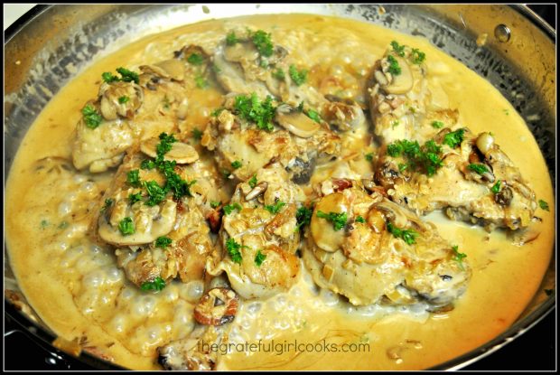 Coq au vin is served, garnished with chopped parsley.