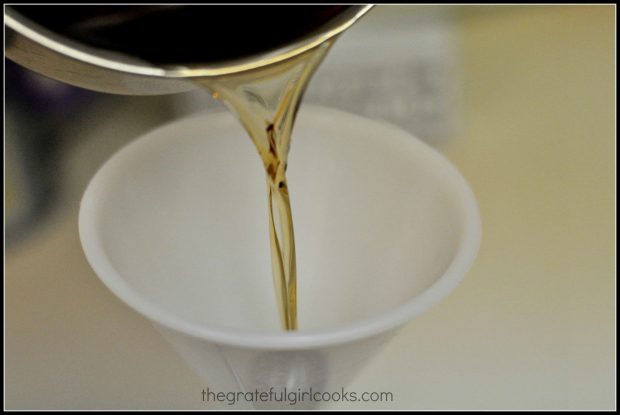 Pouring the homemade amaretto into a funnel, then into the bottle.