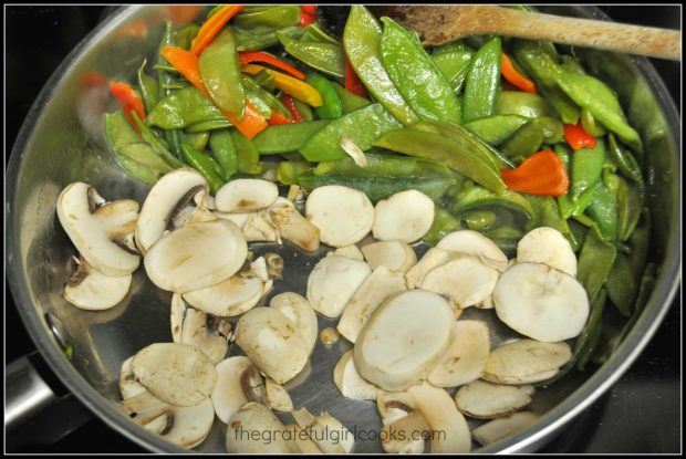 Sugar snap pea stir fry with mushrooms and bell peppers cooking in skillet.