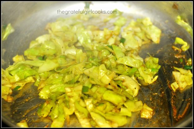 Soy sauce is added to the cooked down cabbage and green onions.