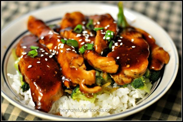 Teriyaki chicken rice bowl is topped with chicken, glaze, green onions and sesame seeds before serving.