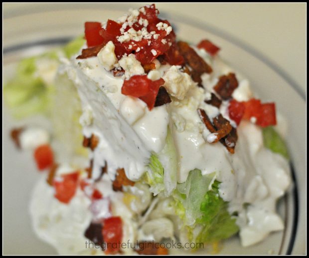 Cold crisp lettuce wedge is topped with blue cheese dressing, bacon, tomato and crumbled blue cheese