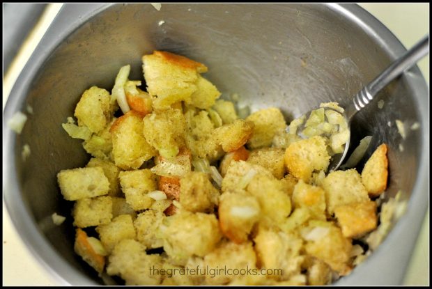 Stuffing for baked pork chops, made with soft bread cubes, butter and onions in small metal bowl