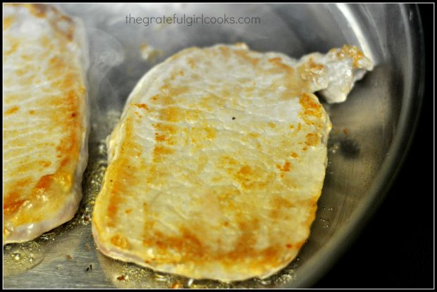 Pork chops are browned on both sides in skillet before being baked.