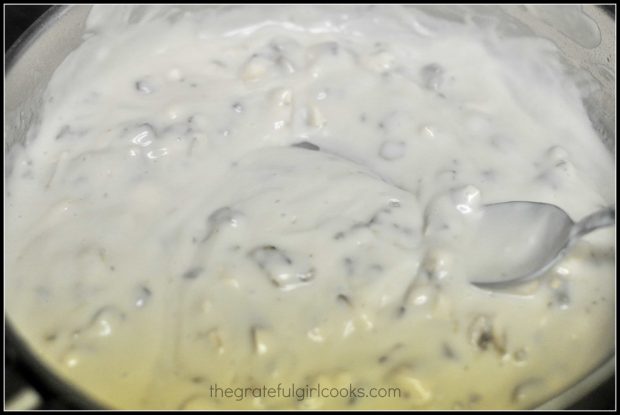 Creamy mushroom sauce heating on stove top in skillet before toppng pork chops.