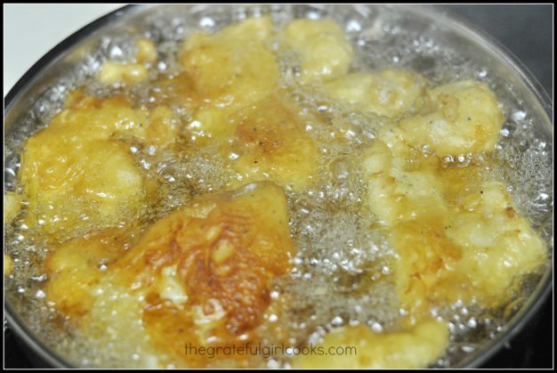 Beer battered fish pieces are cooked in hot oil
