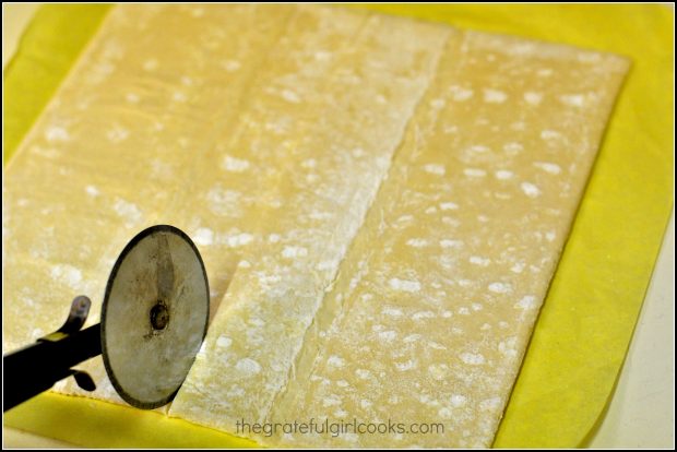 Cutting the pastry dough with a pizza cutter.