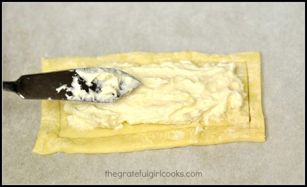 Cream cheese filling is spread out in inner rectangle of the dough.