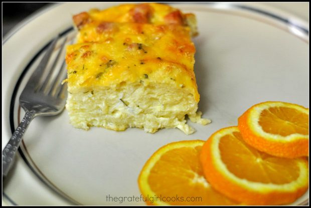 A piece of ham 'n cheese breakfast souffle on a plate, with orange slices.