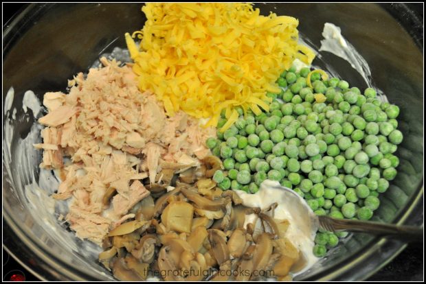 Tuna, mushrooms, cheddar cheese and peas are added to sauce for tuna noodle casserole.