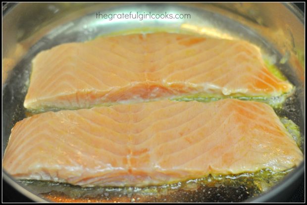 Salmon fillets are pan-seared in skillet
