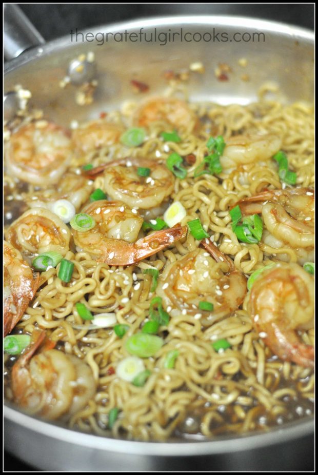 The shrimp and noodles in spicy garlic sauce is heated through in the skillet.