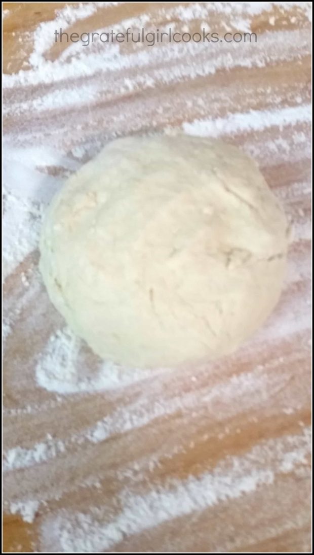 The dough rests on a floured surface before shaping.