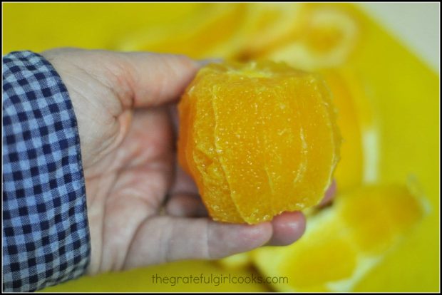 Cutting the peel off the orange before slicing into chunks to add to salad.