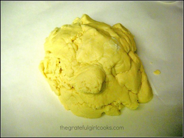 The dough for Spring flower sugar cookies is resting on parchment paper.