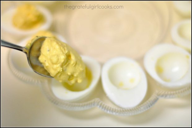 Spooning deviled egg filling into hard boiled egg whites