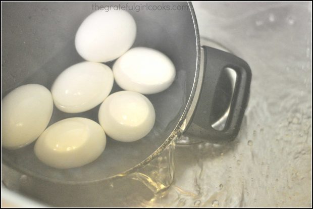 Hot water being poured off of eggs from pan