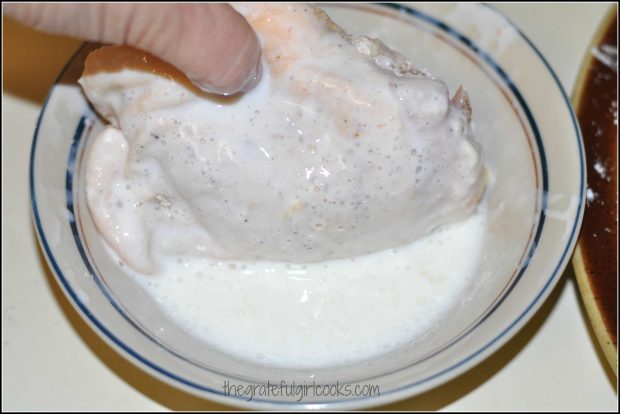 Dredging the chicken in buttermilk before frying.