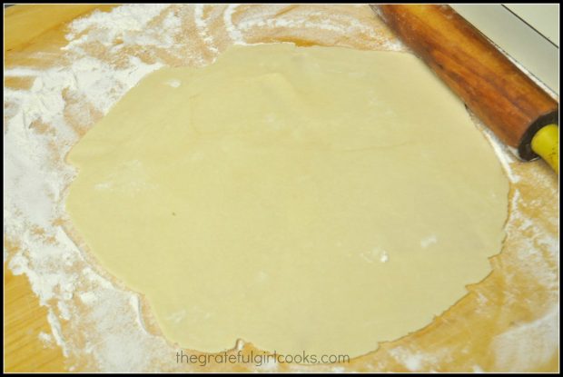 Pie crust dough is rolled out into a large circle on floured surface.