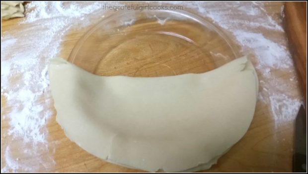 Dough is transferred to a pie pan, and then unfolded.