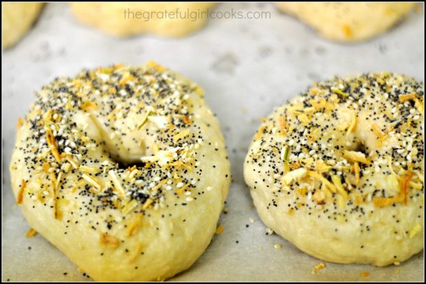 Boiled bagels are topped with everything mix before baking.