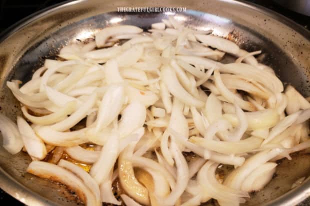 Sliced onions are cooked until tender in a large skillet.