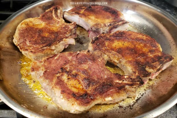 After the bottom is browned, the pork chops are turned over to cook the other side.