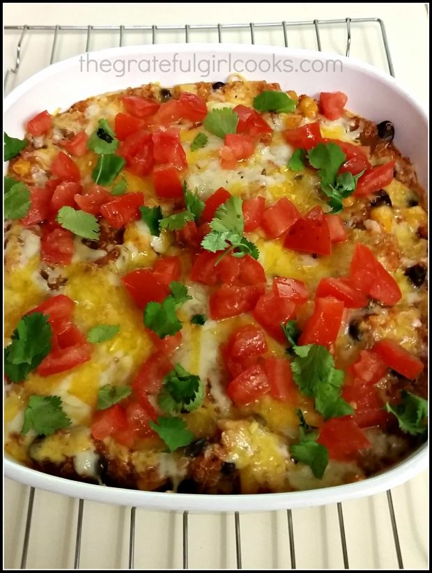 Baked quinoa enchilada casserole is garnished with cilantro and tomatoes.