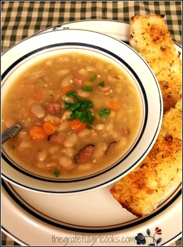 Bowl of ham and bean soup with garlic bread on side