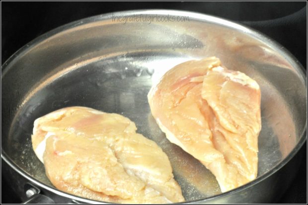 Raw chicken breasts are pan-seared in oil, to brown them.