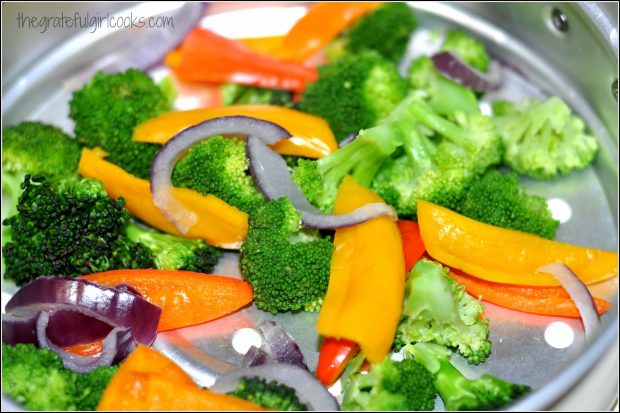 Broccoli, orange and red bell peppers, and red onions are cooked for this dish.