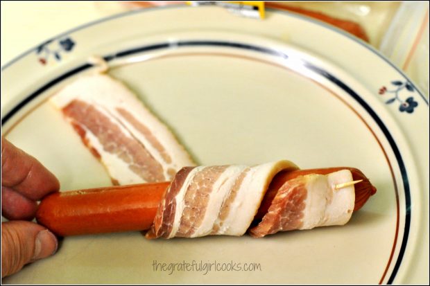 Wrapping hot dog weiner with tightly wound raw bacon strip