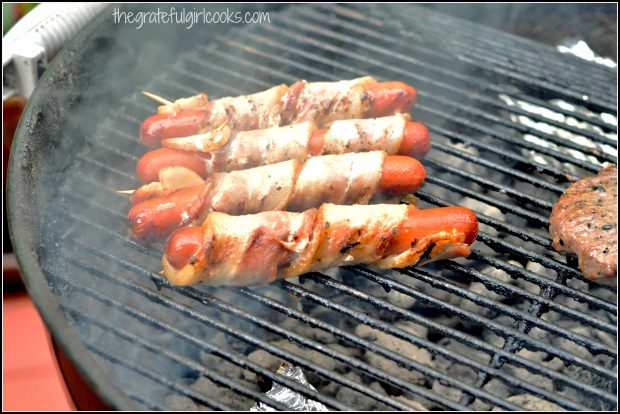 Four hot dogs grilled with bacon wrap.