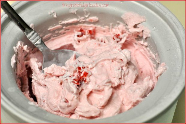 Spoonful of homemade strawberry ice cream, in cannister.