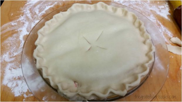 A top crust is placed on top of melba pie filling, and edges of crust are crimped.