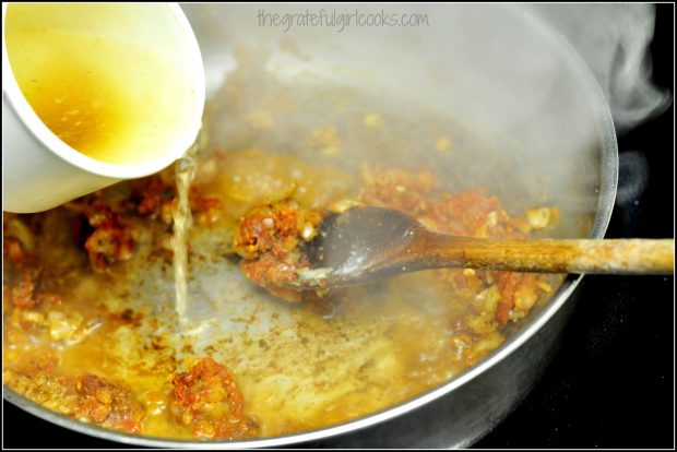 Chicken stock added to pork paprikash sauce in skillet