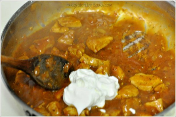 Sour cream is added to pork paprikash in skillet.